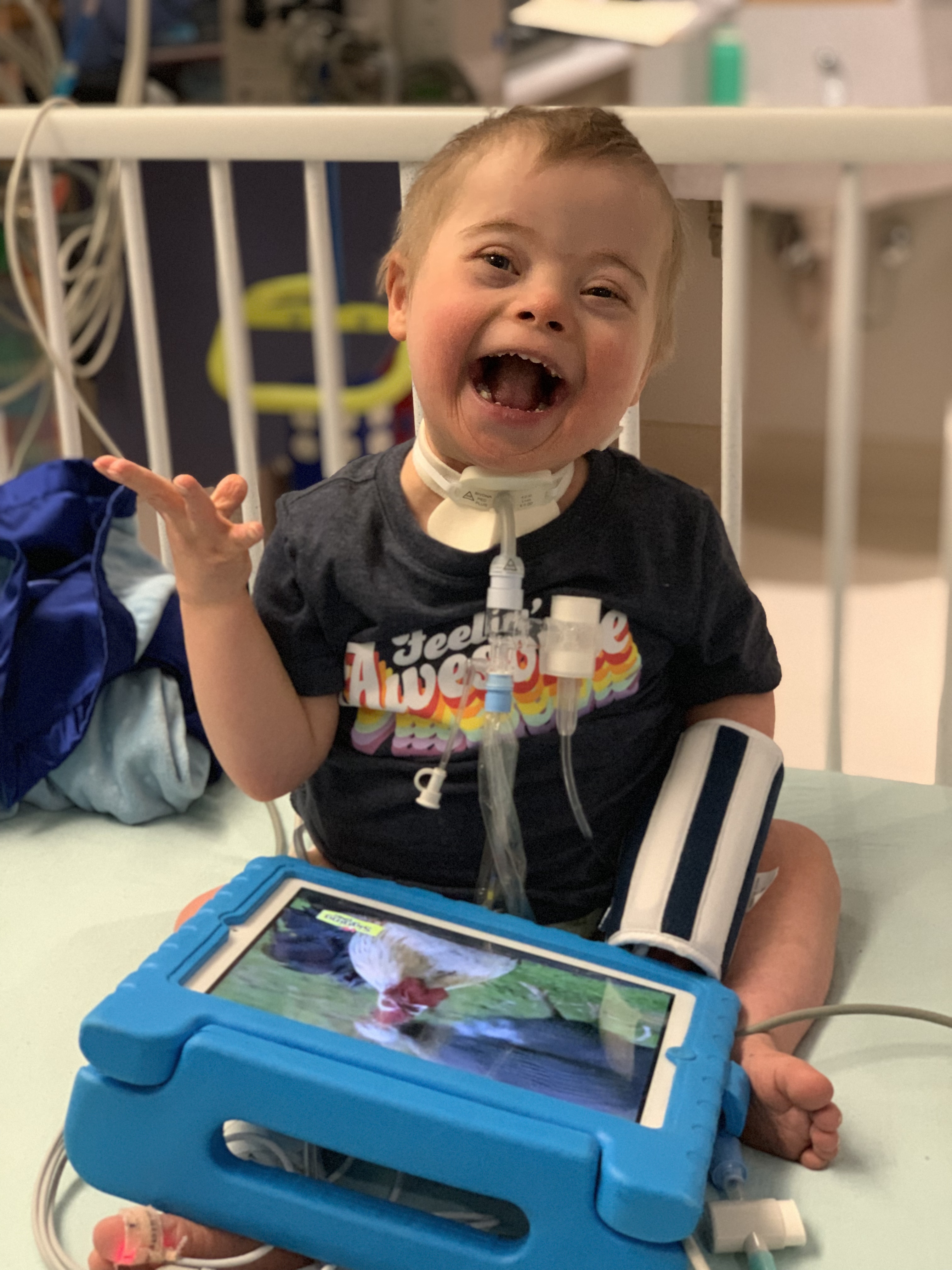 Trach Child Happy in Hospital Crib  with an iPad 